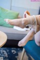 A woman is putting on a pair of white stockings.