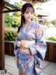 A woman in a blue kimono posing for a picture.