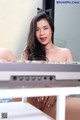 A woman sitting on top of a desk next to a keyboard.