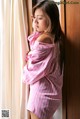 A woman in a pink and white striped shirt leaning against a window.