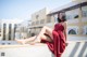 A woman in a red dress sitting on a ledge.