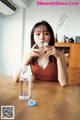 A woman sitting at a table drinking water from a glass.