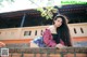 A woman leaning against a brick wall in front of a building.