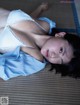 A woman laying on the floor in a white bra and blue shirt.