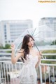 A woman in a white dress holding an umbrella.