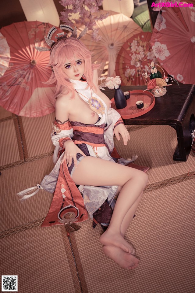 A woman in a kimono sitting on the floor with a sword.