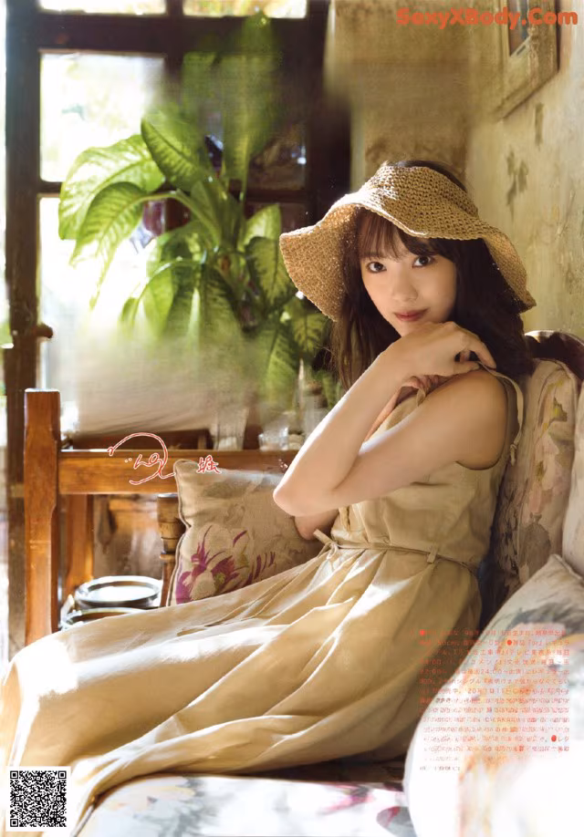 A woman sitting on a couch wearing a straw hat.