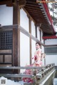 A woman in a kimono sitting on a wooden bridge.