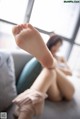 A woman sitting on a couch with her feet up.