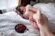 A woman laying on a bed next to a bowl of cherries.