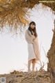 A woman standing in front of a tree in the desert.