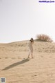 A woman standing on top of a sand dune.