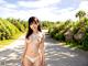 A woman in a white bikini standing on a road.