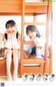 A couple of young women sitting on top of a bunk bed.