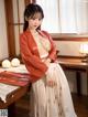 A woman in a red kimono sitting at a table.