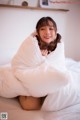 A woman laying on a bed covered in a white blanket.