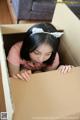 A young woman is peeking out of a cardboard box.