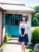 A woman in a blue skirt and white shirt posing in front of a house.