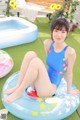 A woman in a blue swimsuit sitting on an inflatable pool float.