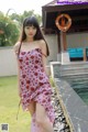 A woman in a pink dress standing next to a pool.