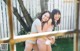 A couple of women standing next to each other near a fence.