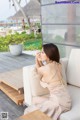 A woman sitting on a white couch next to a pool.