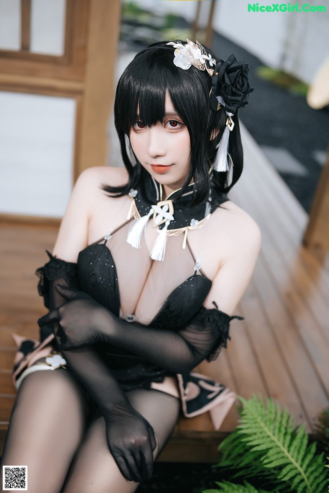 A woman in a black lingerie sitting on a wooden bench.