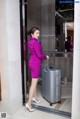 A woman in a purple suit with a suitcase.