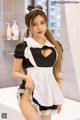 A woman in a maid outfit posing in a bathroom.