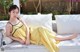 A woman in a yellow dress laying on a white couch.